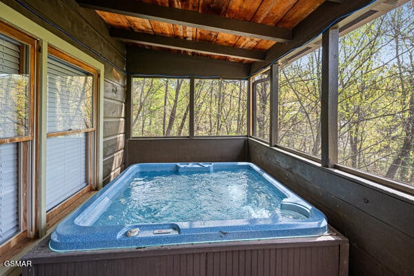 sunroom with a jacuzzi and beamed ceiling