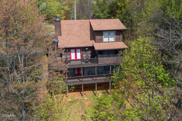 exterior space with a forest view, a chimney, and a balcony