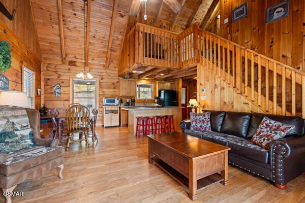 living area featuring high vaulted ceiling, wooden ceiling, light wood-style floors, and wooden walls