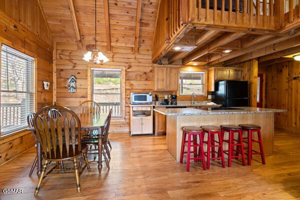 kitchen featuring wood walls, a wealth of natural light, freestanding refrigerator, and white microwave