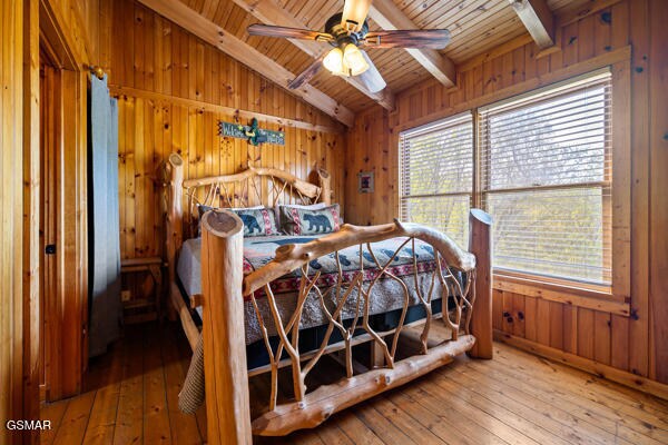 bedroom featuring hardwood / wood-style floors, lofted ceiling with beams, wooden ceiling, and wooden walls