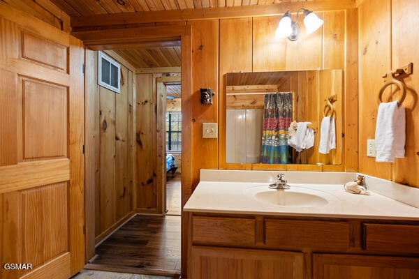 bathroom with beamed ceiling, wooden walls, wood finished floors, and wooden ceiling