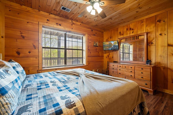 bedroom with wood ceiling, wood walls, wood finished floors, and visible vents