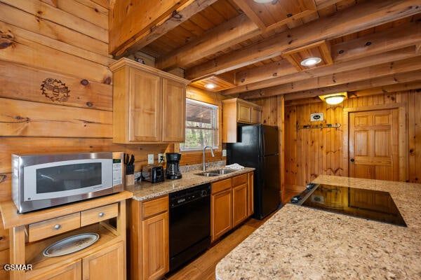 kitchen featuring wooden walls, a sink, light stone countertops, wood ceiling, and black appliances