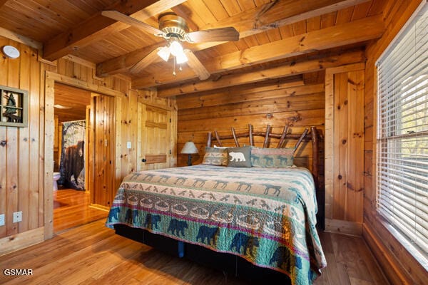 bedroom featuring wood ceiling, wooden walls, wood finished floors, and beam ceiling