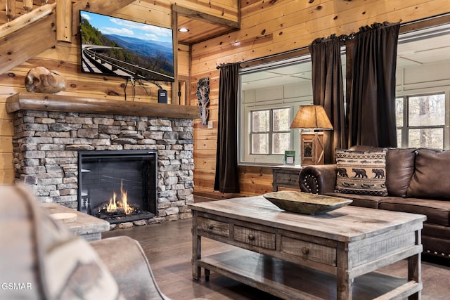 living room with wood-type flooring, a fireplace, a healthy amount of sunlight, and wood walls