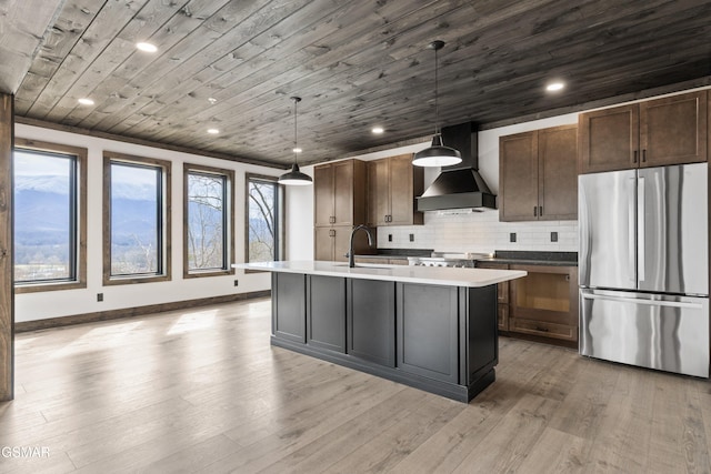3540 Mountain Tyme Way, Sevierville, TN 37862 - kitchen featuring freestanding refrigerator, wall chimney exhaust hood, a sink, an island with sink, and light wood-style floors
