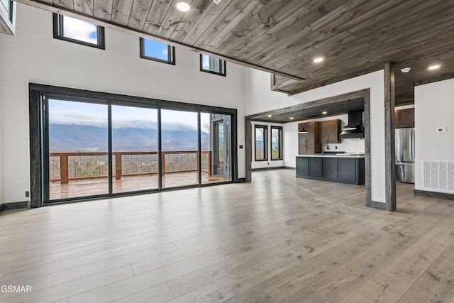 3540 Mountain Tyme Way, Sevierville, TN 37862 - unfurnished living room featuring a towering ceiling, a sink, light wood-style floors, wooden ceiling, and baseboards