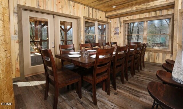 dining space featuring french doors, dark wood-type flooring, wood walls, and wooden ceiling