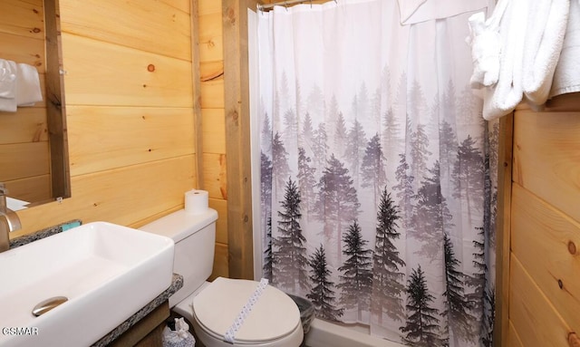 bathroom featuring sink, toilet, a shower with curtain, and wooden walls