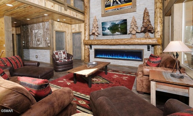 living room featuring a high ceiling, wood walls, and a stone fireplace