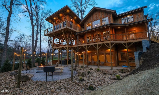 back house at dusk featuring a patio area, an outdoor fire pit, and a balcony