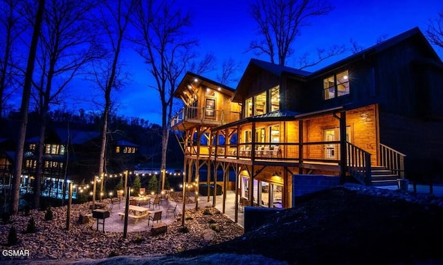 back house at twilight featuring a patio area, a fire pit, and a balcony