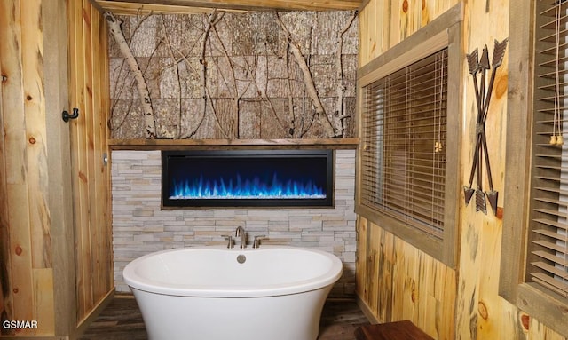 bathroom featuring a washtub and wooden walls