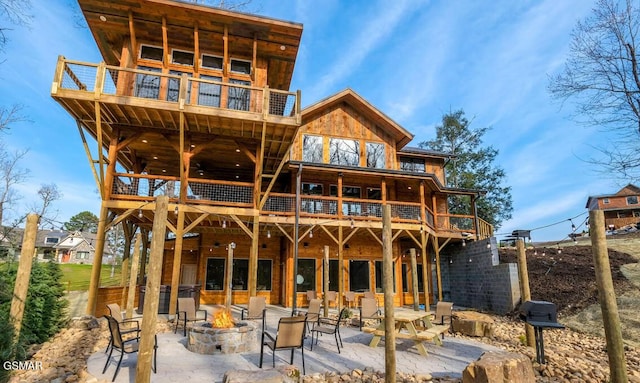 back of house with a patio, a balcony, and a fire pit