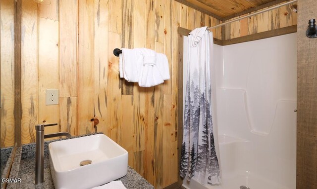 bathroom featuring sink, wood walls, a shower with shower curtain, and wooden ceiling