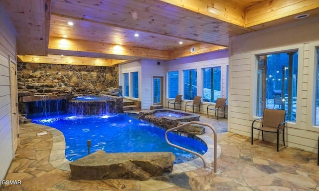 view of swimming pool with pool water feature and a hot tub