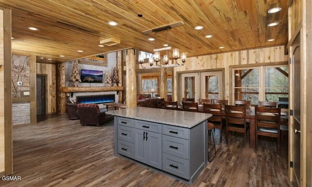 kitchen with light stone countertops, wooden ceiling, french doors, and decorative light fixtures