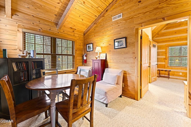 dining area with visible vents, carpet floors, lofted ceiling with beams, wood walls, and wooden ceiling