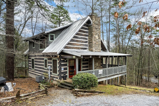 view of front facade featuring a porch, metal roof, central AC unit, and a chimney