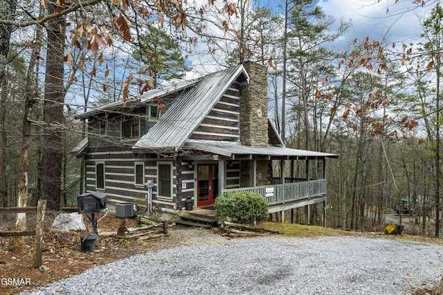 view of front facade with central air condition unit, a porch, a chimney, and metal roof