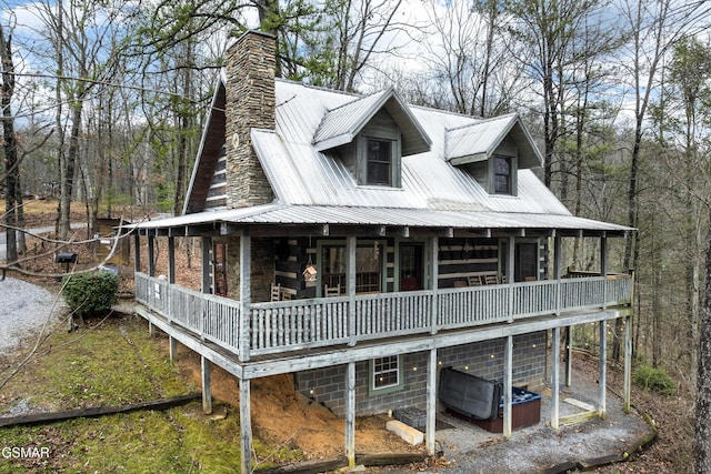 view of front of home featuring a chimney, stone siding, and metal roof