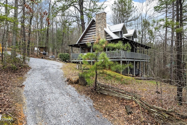 view of home's exterior with driveway, a chimney, and metal roof