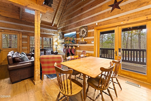 dining room with visible vents, light wood-style flooring, french doors, and wooden walls