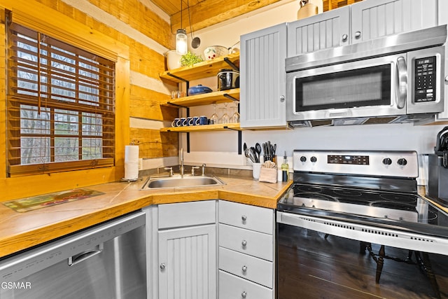 kitchen with appliances with stainless steel finishes, open shelves, and a sink