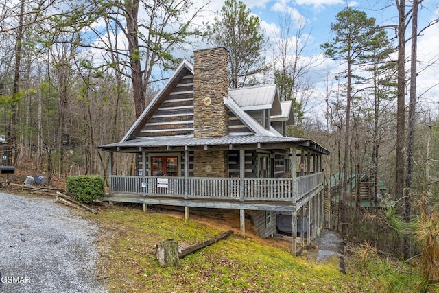 view of front of home featuring a porch, a chimney, and metal roof