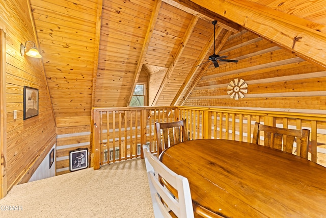 unfurnished dining area featuring wooden walls, a ceiling fan, vaulted ceiling with beams, wooden ceiling, and carpet flooring