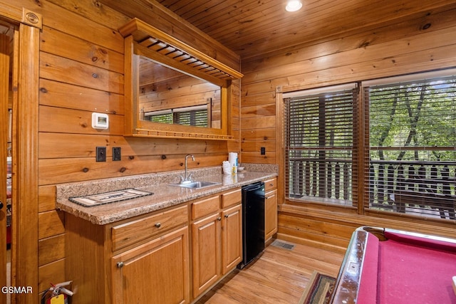 kitchen with light hardwood / wood-style floors, light stone counters, wooden walls, and sink