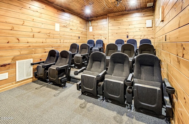 carpeted home theater room with wooden ceiling and wood walls