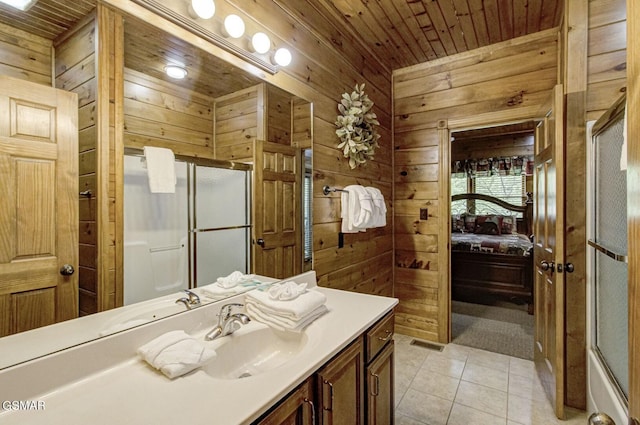 bathroom featuring tile patterned flooring, vanity, a shower with door, and wood walls