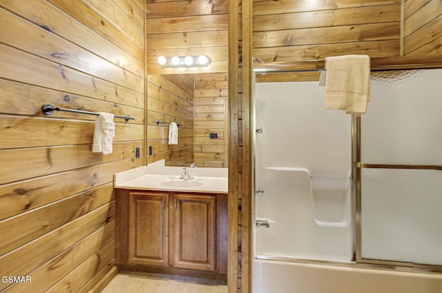 bathroom featuring tile patterned flooring, vanity, combined bath / shower with glass door, and wooden walls