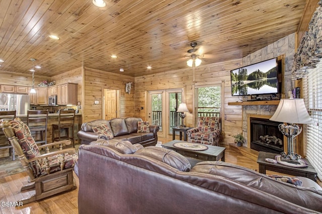 living room featuring a stone fireplace, wooden ceiling, and light wood-type flooring