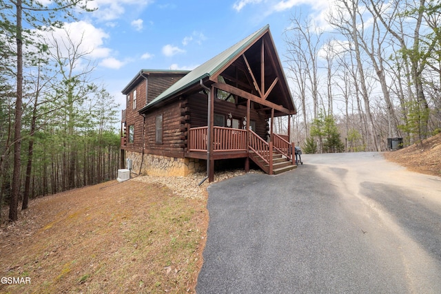log cabin with aphalt driveway, a porch, and log siding