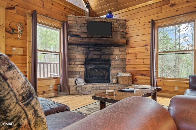 living room featuring lofted ceiling, a fireplace, wood finished floors, and wooden walls