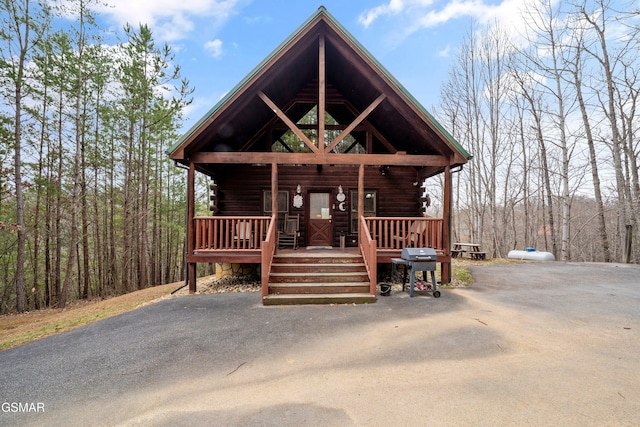 log cabin featuring covered porch and log exterior