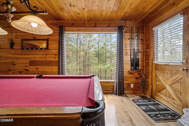 playroom with light wood-style flooring, wooden ceiling, a wealth of natural light, and wooden walls