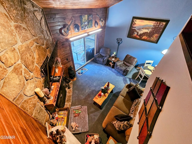 carpeted living room featuring lofted ceiling, wood ceiling, and wooden walls