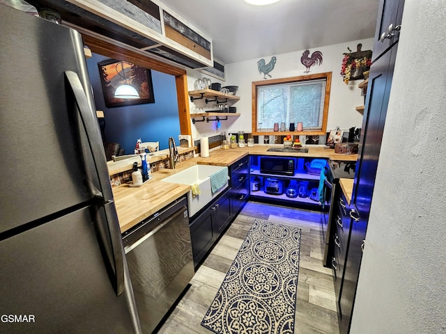 kitchen with sink, butcher block counters, and black appliances