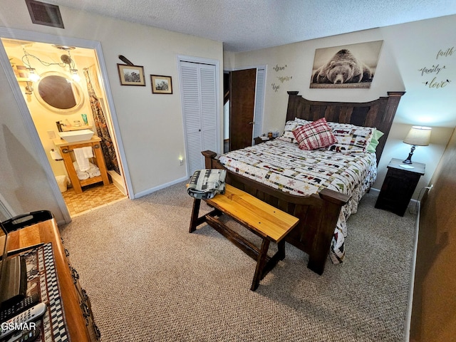 carpeted bedroom featuring ensuite bathroom and a textured ceiling