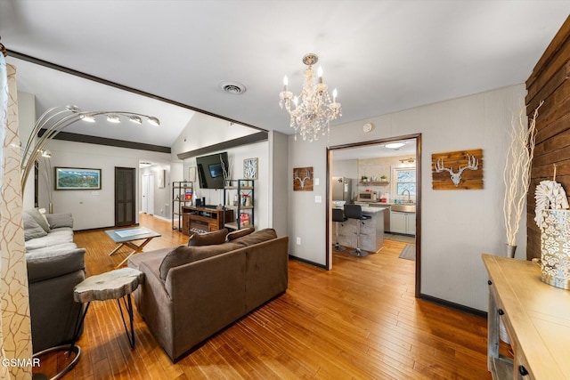 living room featuring wood-type flooring, vaulted ceiling, and a notable chandelier