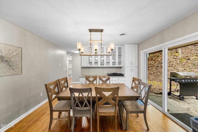 dining area with plenty of natural light, light hardwood / wood-style floors, and a chandelier