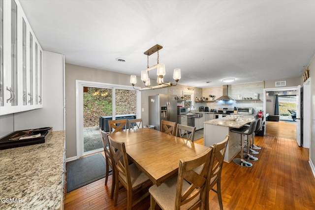 dining space featuring hardwood / wood-style flooring, a wealth of natural light, and a chandelier