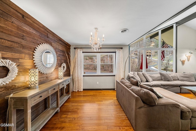 living room with lofted ceiling, a chandelier, and light wood-type flooring