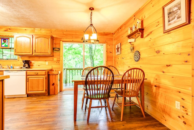 dining area featuring wood walls, a chandelier, and light wood-type flooring