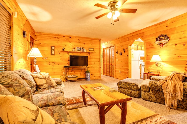 carpeted living room with ceiling fan and wood walls