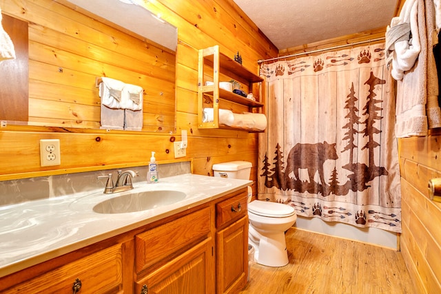 full bathroom with hardwood / wood-style flooring, wooden walls, a textured ceiling, and toilet